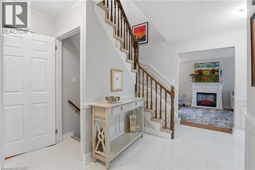 Stairway with a glass covered fireplace, a textured ceiling, and tile patterned floors - 668 Tomahawk Crescent, Ancaster, ON - Indoor Photo Showing Other Room