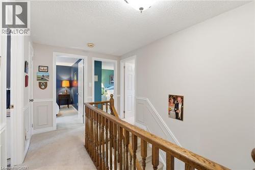 Hallway with an upstairs landing, light carpet, a textured ceiling, a decorative wall, and wainscoting - 668 Tomahawk Crescent, Ancaster, ON - Indoor Photo Showing Other Room