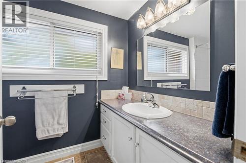 Bathroom featuring vanity, dark tile patterned floors, a shower, and healthy amount of natural light - 668 Tomahawk Crescent, Ancaster, ON - Indoor Photo Showing Bathroom