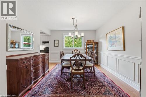Dining room with light wood finished floors, a decorative wall, a chandelier, and wainscoting - 668 Tomahawk Crescent, Ancaster, ON - Indoor Photo Showing Dining Room