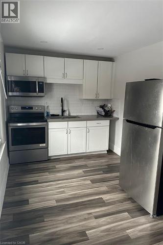 Kitchen featuring white cabinets, dark hardwood / wood-style floors, sink, and appliances with stainless steel finishes - 1090 Cannon Street E, Hamilton, ON - Indoor Photo Showing Kitchen
