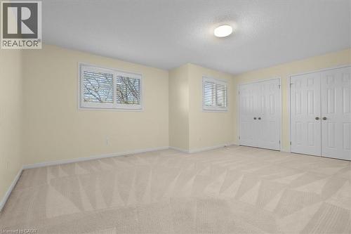 Unfurnished bedroom with light colored carpet, two closets, and a textured ceiling - 90 Westlawn Drive, Hamilton, ON - Indoor Photo Showing Other Room