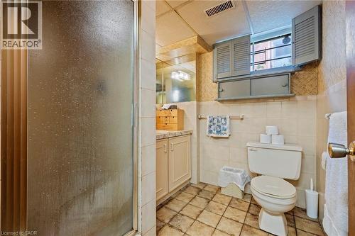 Full bathroom with a stall shower, vanity, wallpapered walls, tile walls, and wainscoting - 40 Bertram Drive, Dundas, ON - Indoor Photo Showing Bathroom