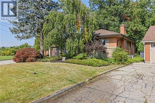 View of front of house featuring brick siding, a chimney, a front yard, and a garage - 40 Bertram Drive, Dundas, ON - Outdoor