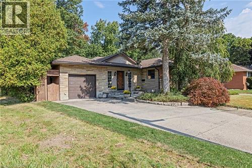 Ranch-style house featuring stone siding, a front yard, a garage, and driveway - 40 Bertram Drive, Dundas, ON - Outdoor