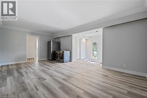 Unfurnished living room with light wood-style floors, crown molding, and washing machine and clothes dryer - 40 Bertram Drive, Dundas, ON - Indoor Photo Showing Other Room