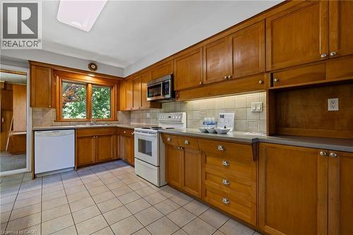 Kitchen featuring white appliances, wood finish cabinets, decorative backsplash, light tile patterned flooring, and light countertops - 40 Bertram Drive, Dundas, ON - Indoor Photo Showing Kitchen