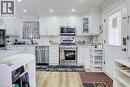 Kitchen featuring white cabinetry, stainless steel appliances, recessed lighting, wood-finish flooring, and a white paneled door with frosted glass - 823 Queensdale Avenue E, Hamilton, ON  - Indoor Photo Showing Kitchen With Upgraded Kitchen 