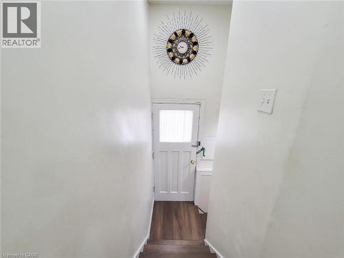 White paneled door with frosted glass window and wood-finish flooring - 823 Queensdale Avenue E, Hamilton, ON - Indoor Photo Showing Other Room