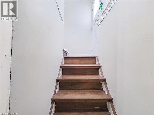 Wood-finish staircase with white risers and light-colored walls - 823 Queensdale Avenue E, Hamilton, ON - Indoor Photo Showing Other Room