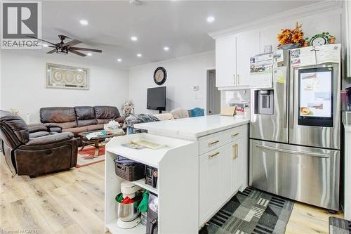 Kitchen with stainless steel fridge with ice dispenser, ornamental molding, a peninsula, light wood finished floors, and open floor plan - 823 Queensdale Avenue E, Hamilton, ON - Indoor
