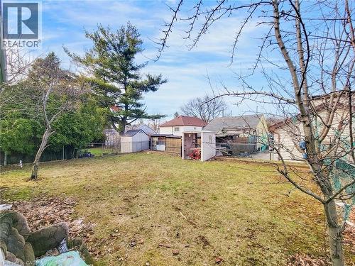 Expansive rear yard featuring a sloped lawn, mature perimeter trees, and two storage sheds - 823 Queensdale Avenue E, Hamilton, ON - Outdoor