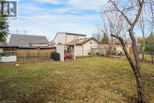 Expansive backyard featuring a natural grass lawn, a dedicated storage shed, and mature perimeter trees - 823 Queensdale Avenue E, Hamilton, ON - Outdoor