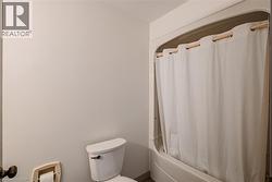 Bathroom featuring toilet and shower / bath combination with curtain - 