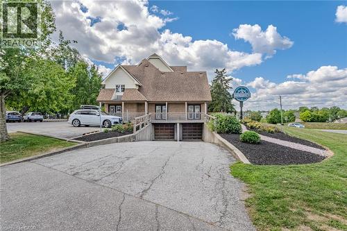 View of front of property with a garage, roof with shingles, a front yard, driveway, and covered porch - 30 John Street, Port Dover, ON 