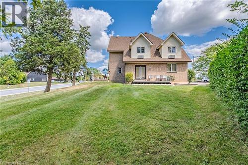 Rear view of property featuring a yard, a deck, and brick siding - 30 John Street, Port Dover, ON 