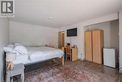 Bedroom featuring dark wood-style floors and white refrigerator - 
