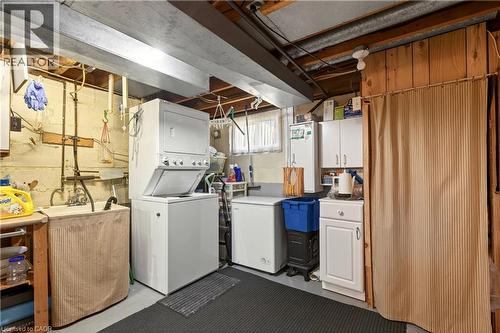 Laundry room featuring cabinet space, concrete flooring, and stacked washer / dryer - 944 Garth Street, Hamilton, ON - Indoor Photo Showing Laundry Room