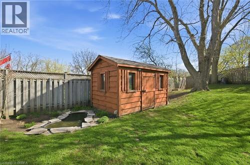 Expansive grassy backyard featuring a wooden shed, a stone-edged pond, a tall privacy fence, and mature trees - 71 Pinecrest Drive, Kitchener, ON - Outdoor
