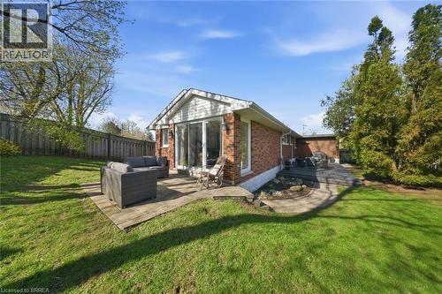 Expansive rear yard featuring a manicured lawn, two distinct patio areas, and a brick exterior with white siding accents - 71 Pinecrest Drive, Kitchener, ON - Outdoor