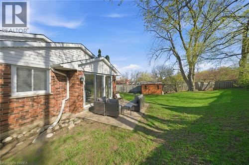 Expansive backyard featuring a large concrete patio, manicured lawn, mature trees, and a wood-paneled shed - 71 Pinecrest Drive, Kitchener, ON - Outdoor