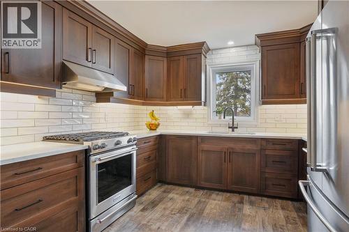 Kitchen featuring stainless steel appliances, light stone counters, dark wood-style flooring, and backsplash - 23247 Beattie Line, Elgin, ON - Indoor Photo Showing Kitchen With Upgraded Kitchen