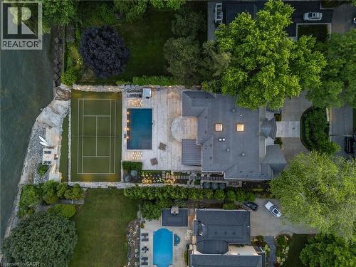Expansive waterside property featuring a tennis court, swimming pool, and stone patio - 140 Secord Lane, Burlington, ON - Outdoor With In Ground Pool
