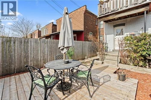 Rear view of house featuring a fenced backyard, outdoor dining area, brick siding, and a wooden deck - 78 Clyde Street, Hamilton, ON - Outdoor