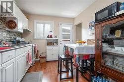 Kitchen featuring white cabinetry, electric range, light wood-type flooring, black microwave, and tasteful backsplash - 