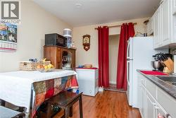 Kitchen featuring white cabinets, black microwave, dark wood finished floors, and freestanding refrigerator - 