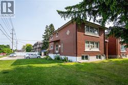 View of property exterior featuring a yard, brick siding, and a balcony - 
