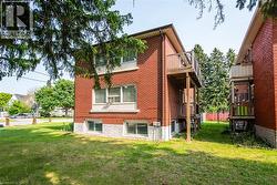 Back of house with a lawn, brick siding, and a balcony - 