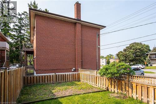 View of property exterior with a chimney, a fenced backyard, brick siding, and a balcony - 129 River Road E, Kitchener, ON - Outdoor With Exterior