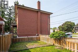 View of property exterior with a chimney, a fenced backyard, brick siding, and a balcony - 