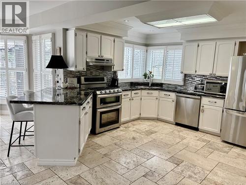 Kitchen featuring stainless steel appliances, a breakfast bar area, a peninsula, white cabinets, and crown molding - 2056 Hadfield Court, Burlington, ON - Indoor Photo Showing Kitchen With Upgraded Kitchen