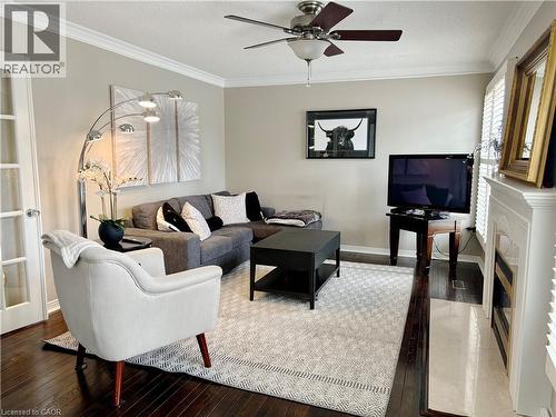 Living area with ornamental molding, hardwood / wood-style floors, ceiling fan, a textured ceiling, and a fireplace - 2056 Hadfield Court, Burlington, ON - Indoor