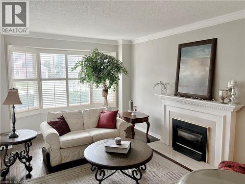 Living area featuring wood finished floors, crown molding, a textured ceiling, and a glass covered fireplace - 2056 Hadfield Court, Burlington, ON - Indoor Photo Showing Living Room With Fireplace