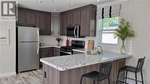 Kitchen with appliances with stainless steel finishes, a peninsula, backsplash, a breakfast bar, and ornamental molding - 24 Macpherson Crescent, Flamborough, ON - Indoor Photo Showing Kitchen With Upgraded Kitchen