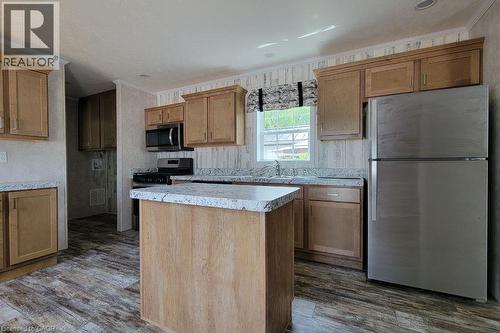 Kitchen with appliances with stainless steel finishes, a center island, dark wood-style flooring, a sink, and light countertops - 77 Park Lane, Flamborough, ON - Indoor Photo Showing Kitchen
