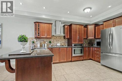Kitchen with stainless steel appliances, a peninsula, dark stone counters, a breakfast bar area, and crown molding - 284 Normanhurst Avenue, Hamilton, ON - Indoor Photo Showing Kitchen