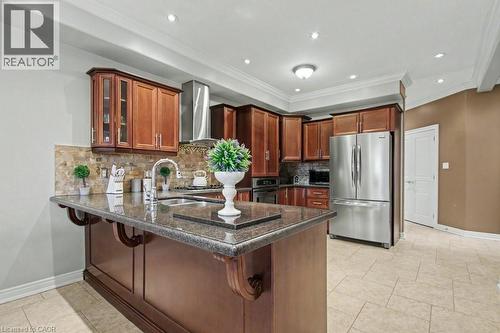 Kitchen with a peninsula, stainless steel appliances, dark stone countertops, a breakfast bar, and glass insert cabinets - 284 Normanhurst Avenue, Hamilton, ON - Indoor Photo Showing Kitchen
