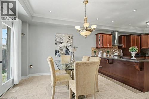 Dining space with a chandelier, crown molding, a tray ceiling, and light tile patterned floors - 284 Normanhurst Avenue, Hamilton, ON - Indoor Photo Showing Dining Room
