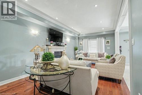 Living room featuring crown molding, a raised ceiling, a glass covered fireplace, dark wood-style flooring, and recessed lighting - 284 Normanhurst Avenue, Hamilton, ON - Indoor