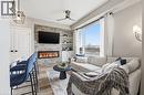 Living area featuring a ceiling fan, built in features, light wood-style flooring, and a stone fireplace - 120 Springvalley Crescent Unit# 203, Hamilton, ON  - Indoor Photo Showing Living Room With Fireplace 
