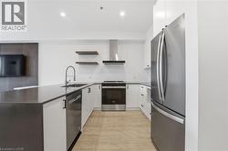 Kitchen featuring a peninsula, stainless steel appliances, white cabinets, open shelves, and recessed lighting - 