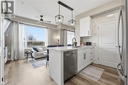 Kitchen with a peninsula, white cabinetry, a breakfast bar, stainless steel appliances, and hanging light fixtures - 