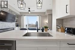 Kitchen featuring backsplash, white cabinetry, light stone countertops, ceiling fan, and dishwasher - 