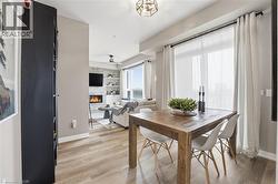 Dining space featuring light wood finished floors, a stone fireplace, and a ceiling fan - 