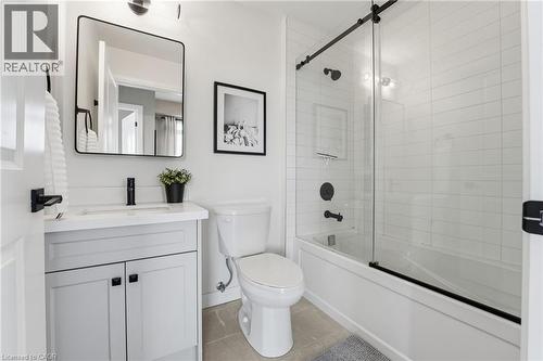 Bathroom with vanity, bath / shower combo with glass door, and light tile patterned flooring - 120 Springvalley Crescent Unit# 203, Hamilton, ON - Indoor Photo Showing Bathroom