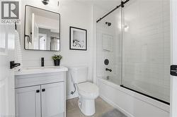 Bathroom with vanity, bath / shower combo with glass door, and light tile patterned flooring - 